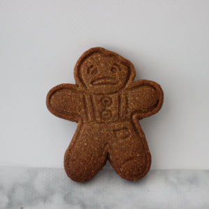 Brown gingerbread man cookie on a white marble surface