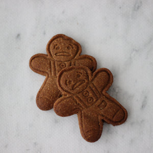 Two gingerbread men cookies on a marble surface